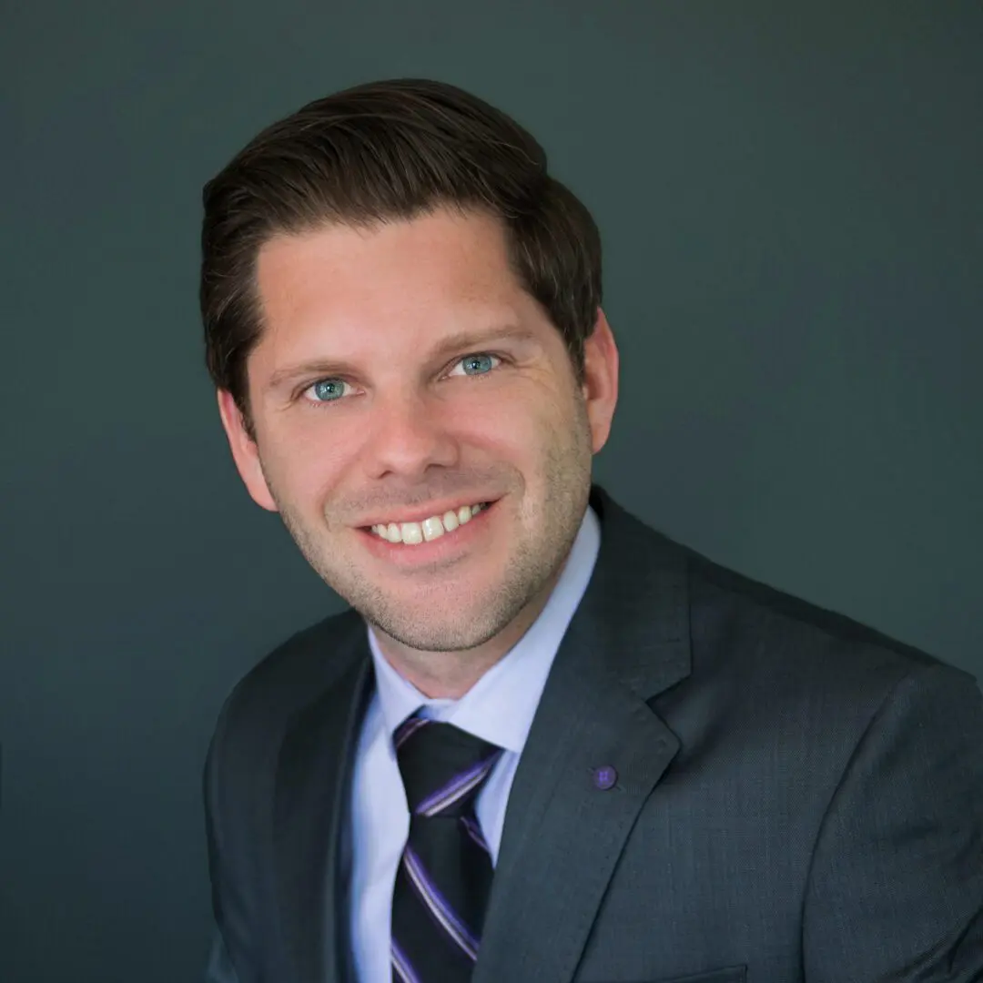 A man in suit and tie smiling for the camera.