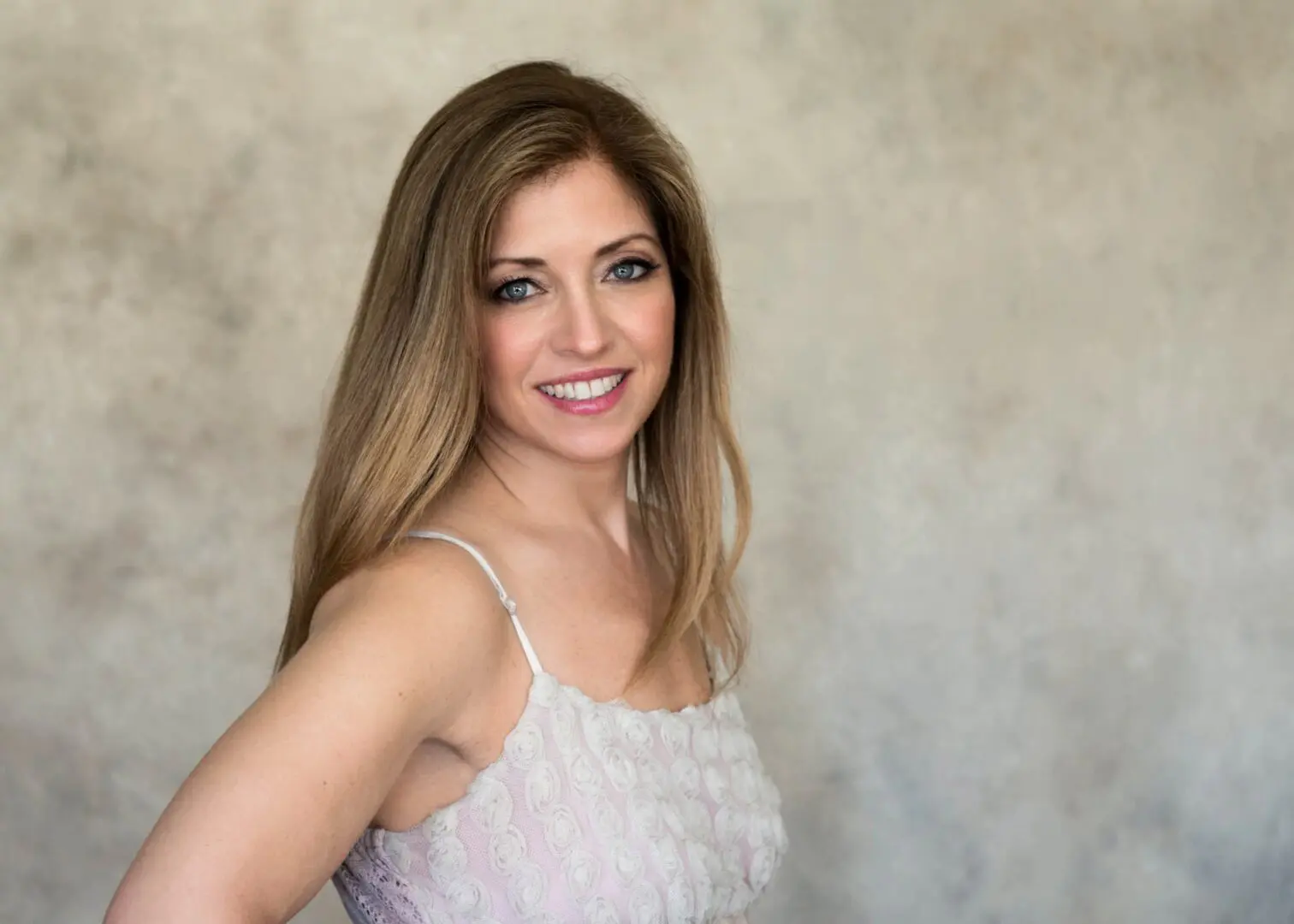 A woman in white dress smiling for the camera.